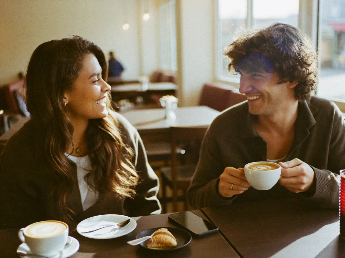 Dos amigos se ríen tomando café en una cafetería